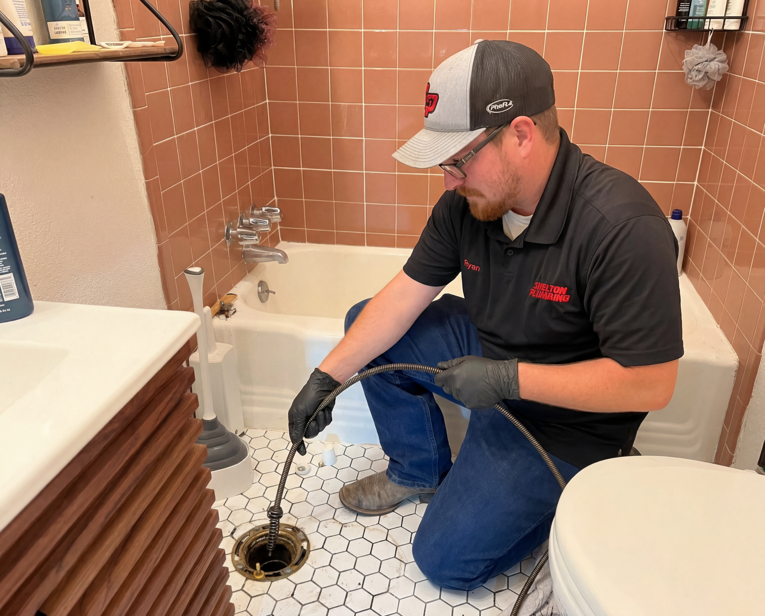 Shelton plumber using snake on pipe